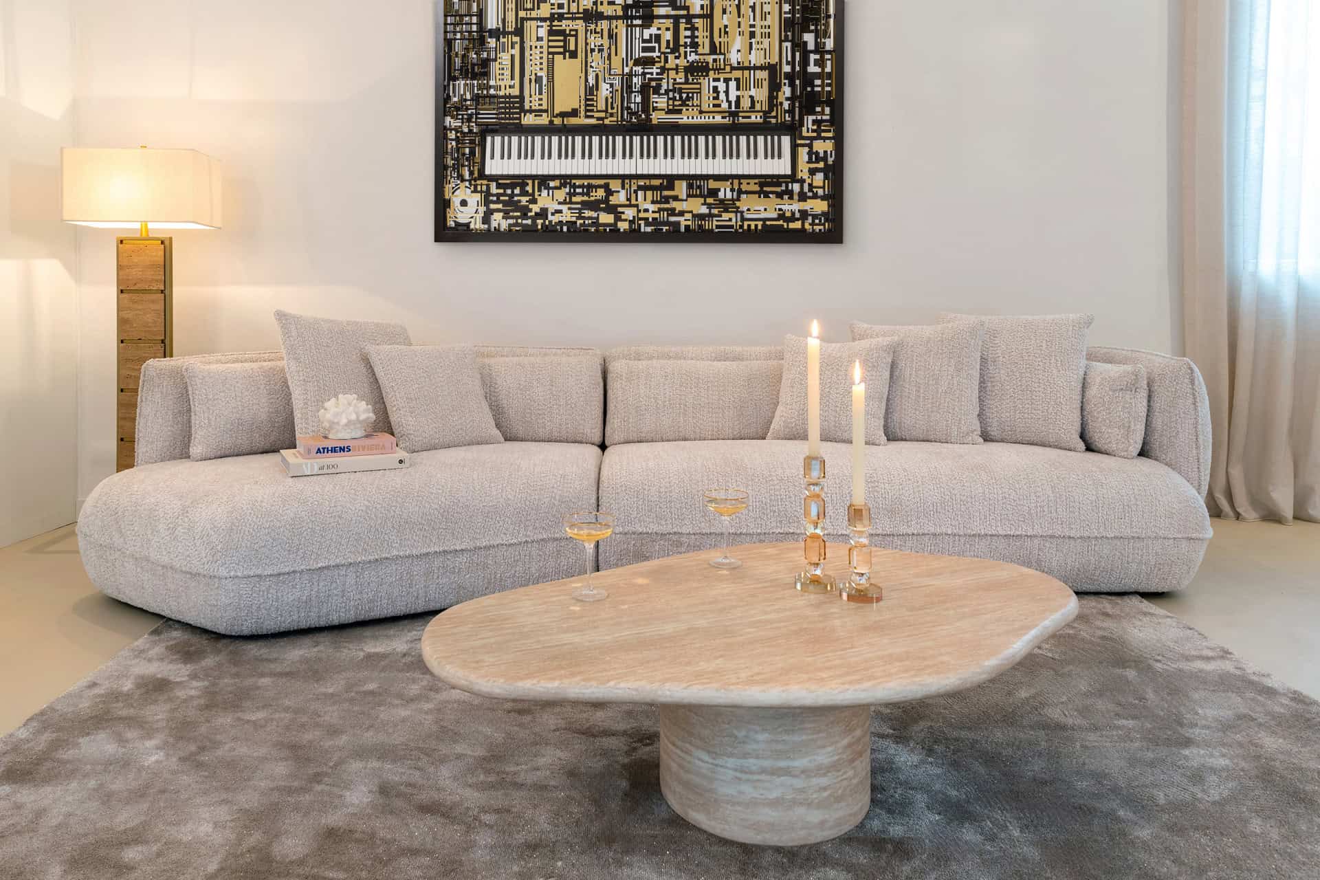 Light beige upholstered Sofa a modern living room with a wooden coffee table and artwork above Sofa.