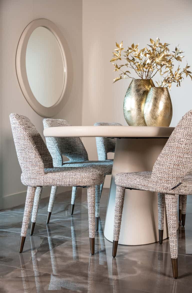 Stijlvolle eetkamertafel met elegante stoffen stoelen en gouden decoratie.