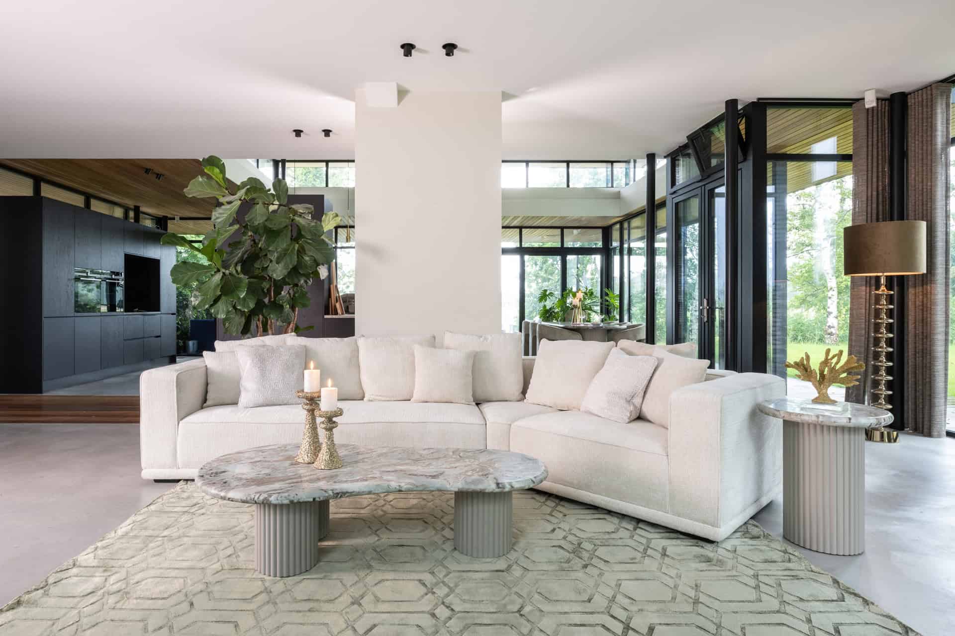 Elegantes Wohnzimmer mit weißem Sofa, Beistelltischen aus Marmor und grünen Pflanzen, modernes Innendesign mit natürlichem Lichteinfall.