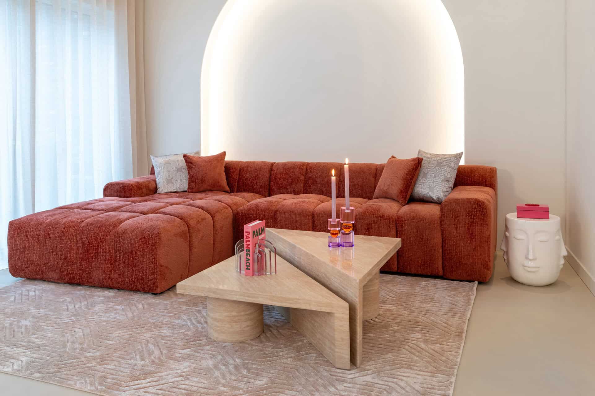 Divano curvo color terracotta sotto una nicchia luminosa, Richmond Interiors