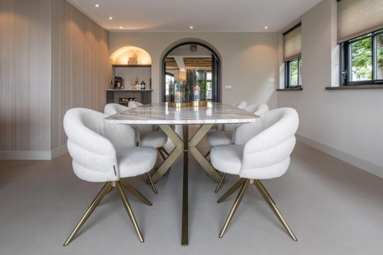 Elegant eettafel met lichte bekleding en goudkleurige poten, modern interieur design.