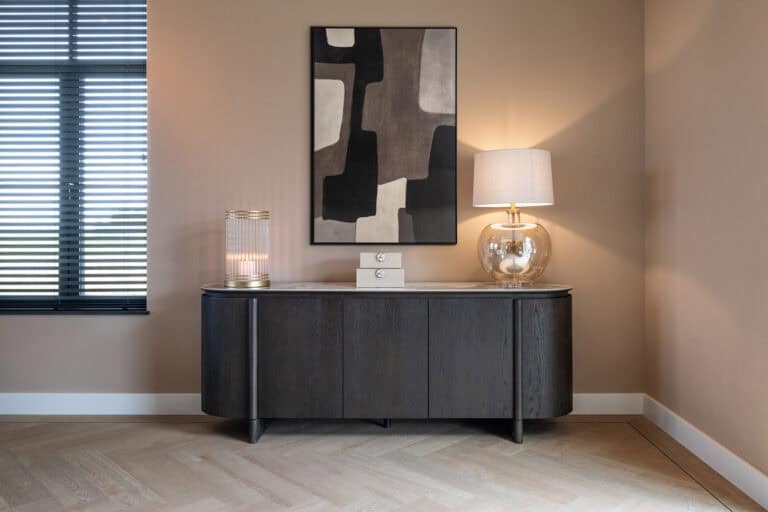 Elegante interieurfoto met zwarte kast, lamp en abstract kunstwerk, perfect voor woningdecoratie.