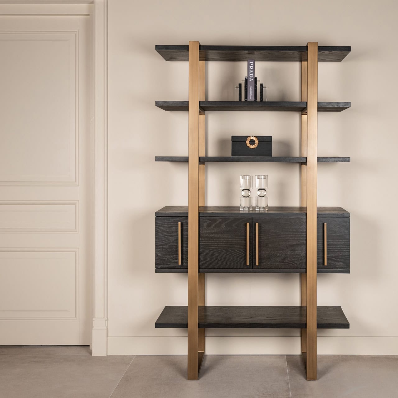 Moderne zwarte houten boekenplank met gouden details en decoratieve accessoires.