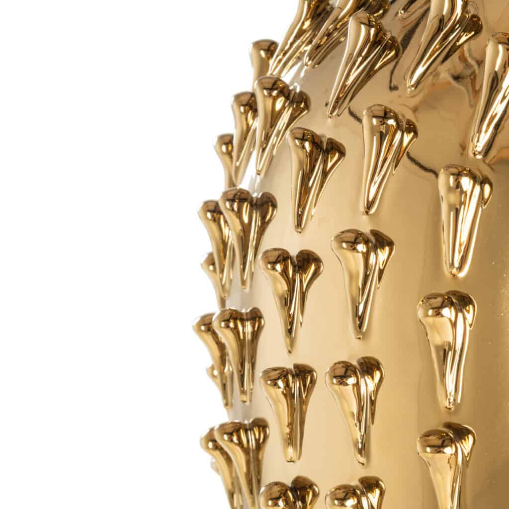 Close-up of a gold vase with decorative accents for interior design.
