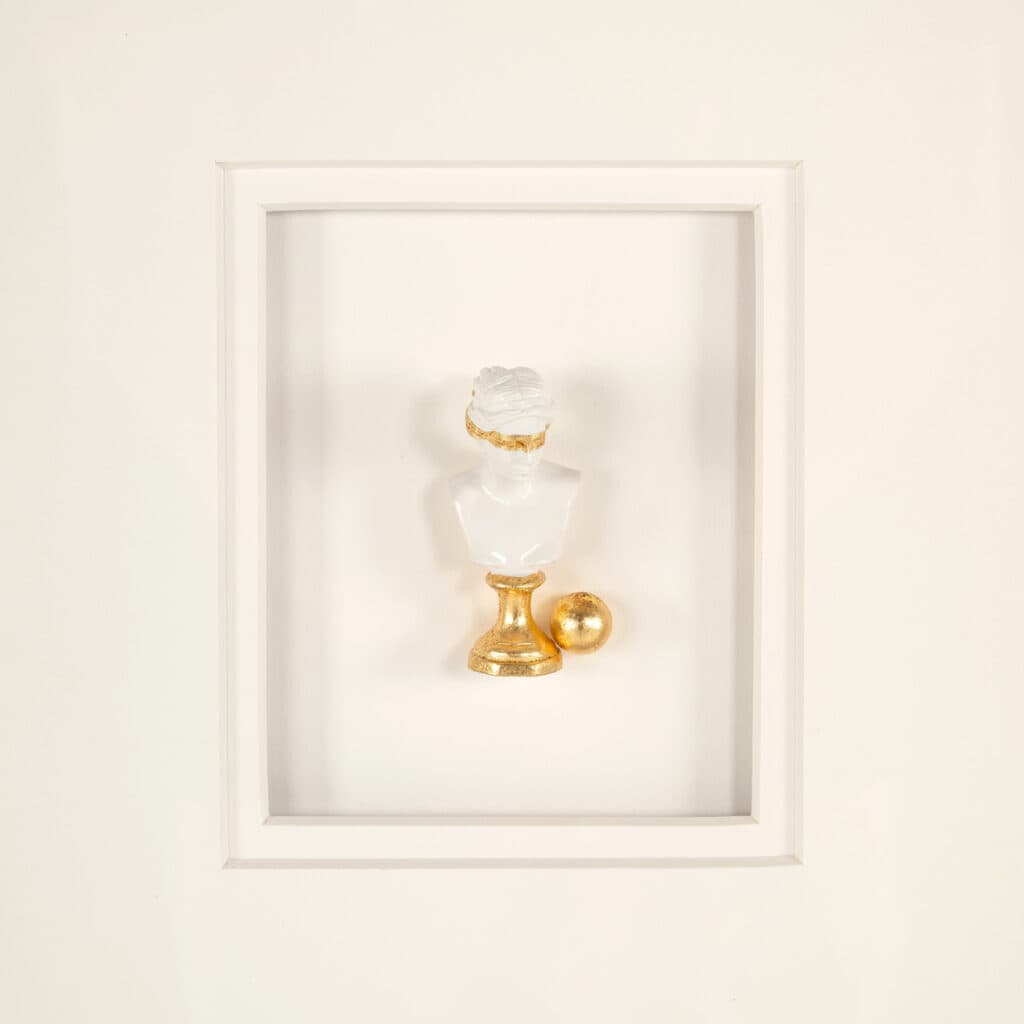Minimalist black-and-white wall decor featuring a sculpture and gold accents.