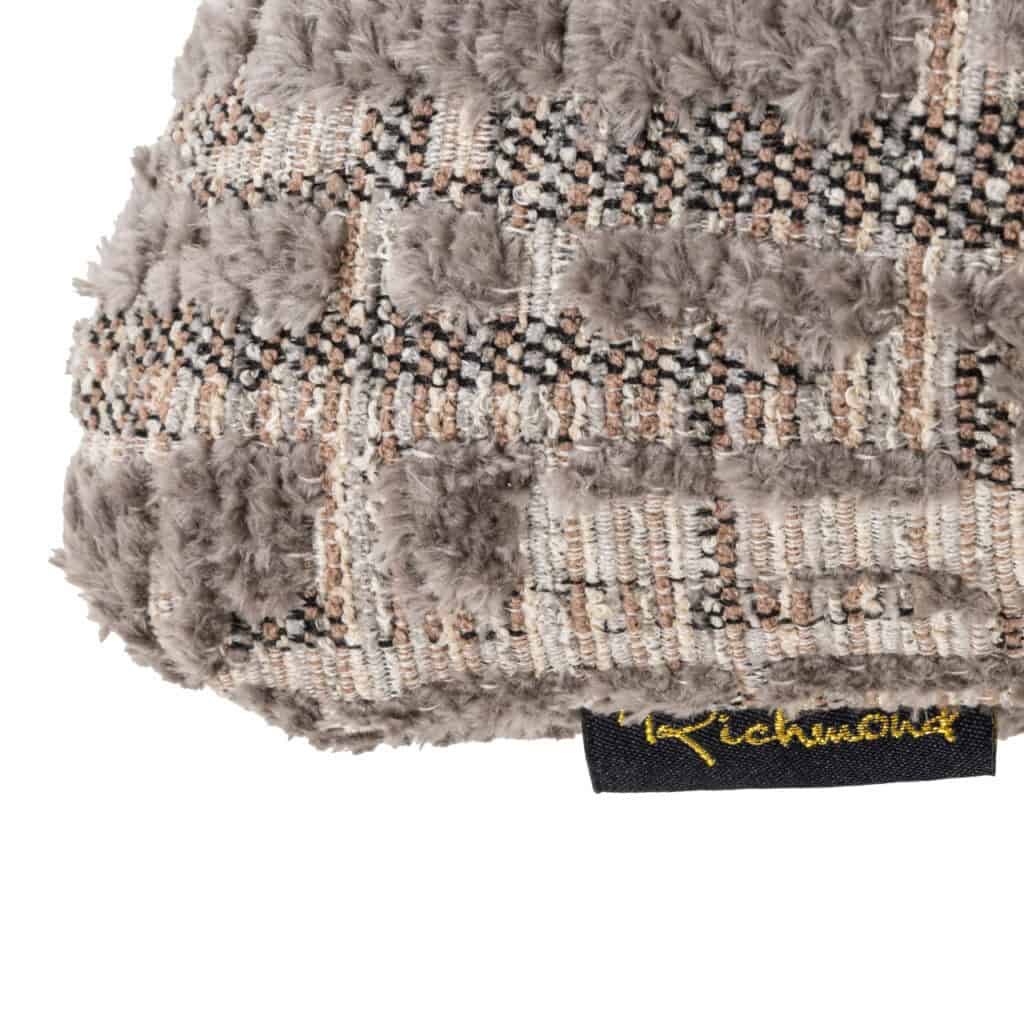 Coussin gris-beige, texturé et en tissus doux.