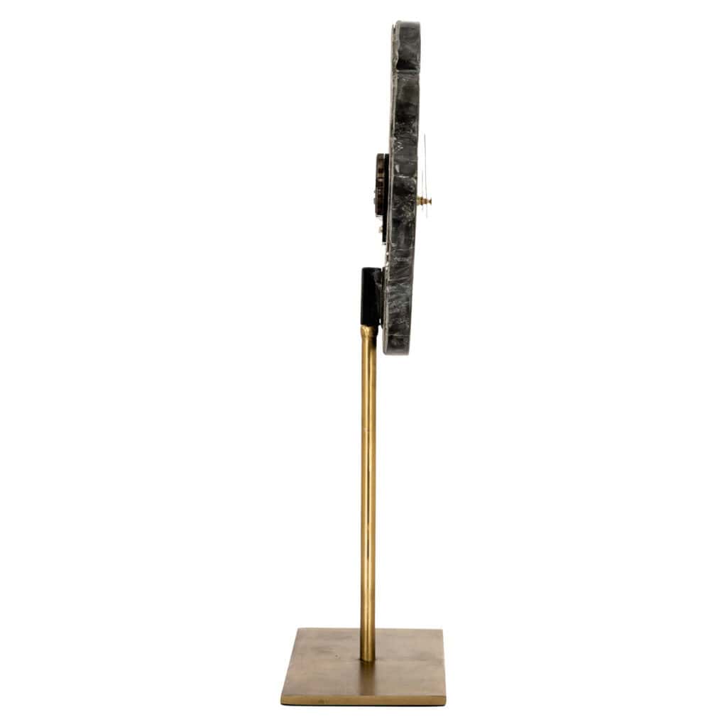Horloge moderne aux gold noires et gold , posée sur un socle en bois.