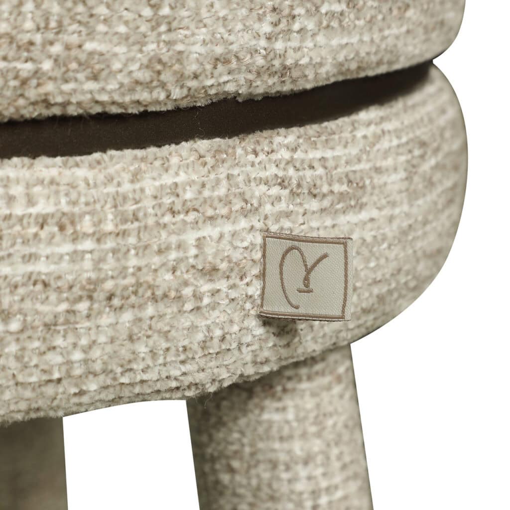 Dichtbij beeld van een zachte, beige gestoffeerde stoel met een label.