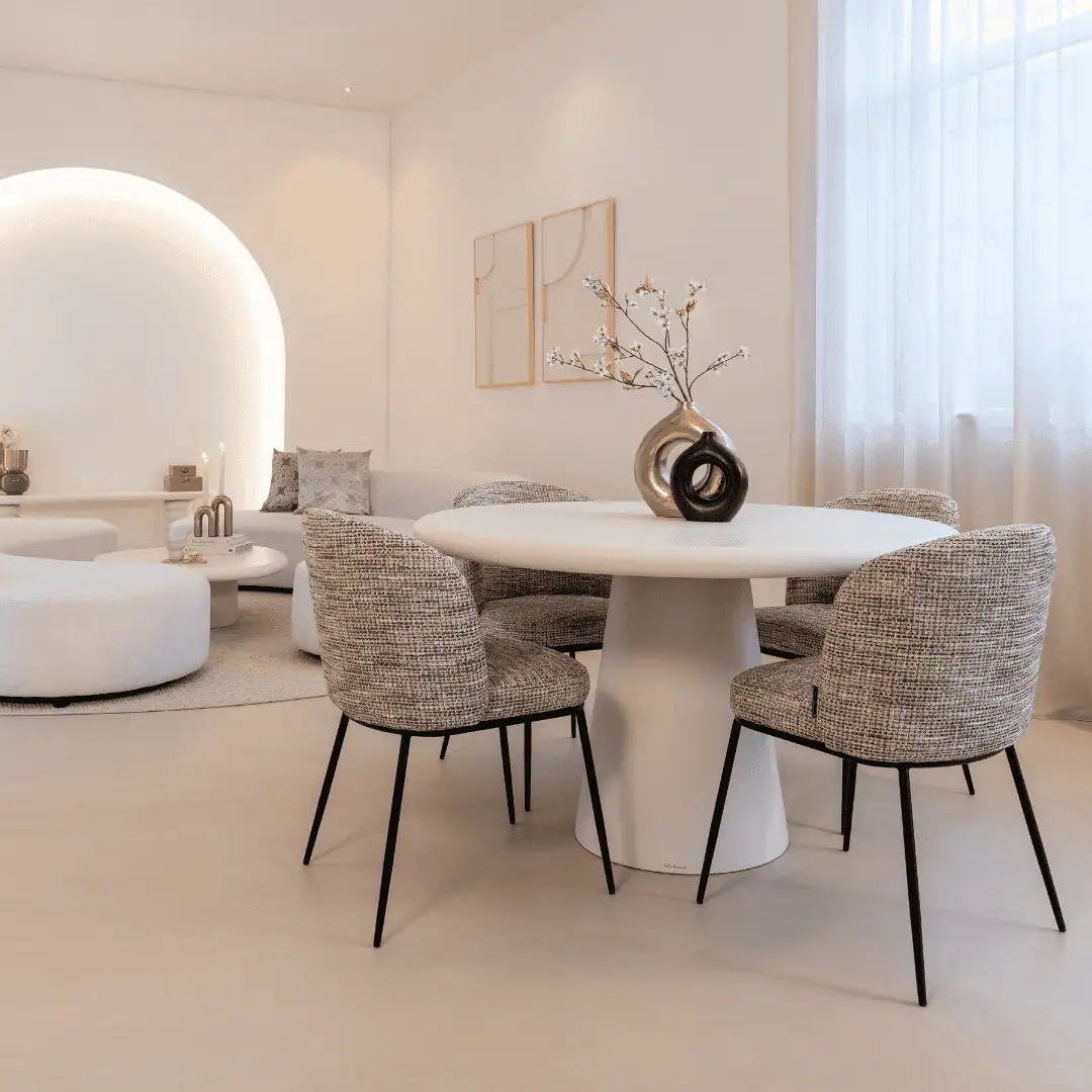 A bright, modern living room with a round table and comfortable chairs.