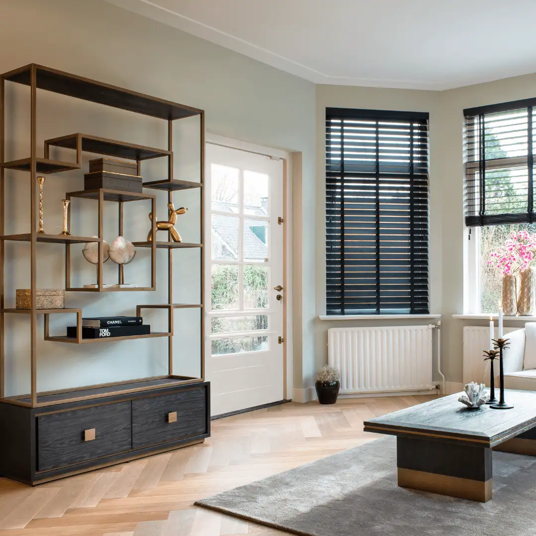 Moderne woonkamer met open houten planken en grote ramen met zwarte jaloezieën.