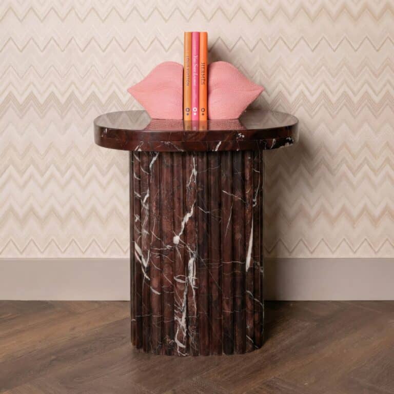 Elegant marmeren bijzettafel met decoratieve kussens en boeken.