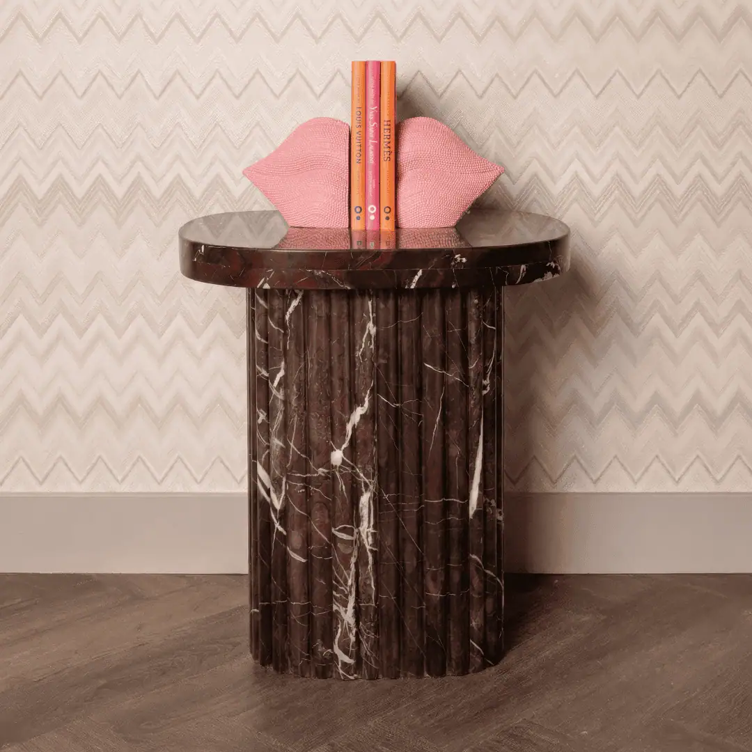 Élégante table d'appoint en marbre, agrémentée de coussins décoratifs et de livres.