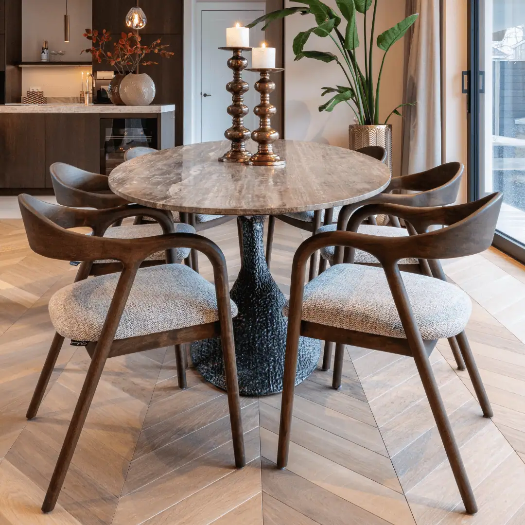 Dining table with four wooden chairs and decorative candles.