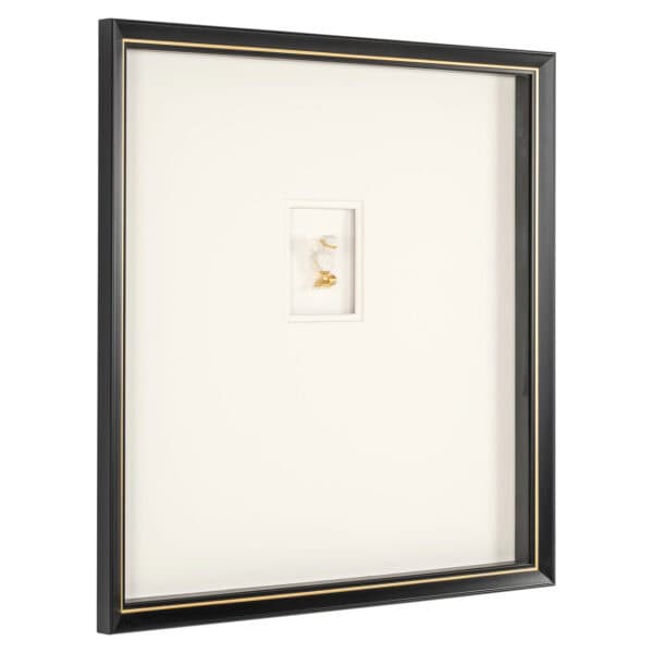 Modern black-and-white wall art with gold accents in a frame.